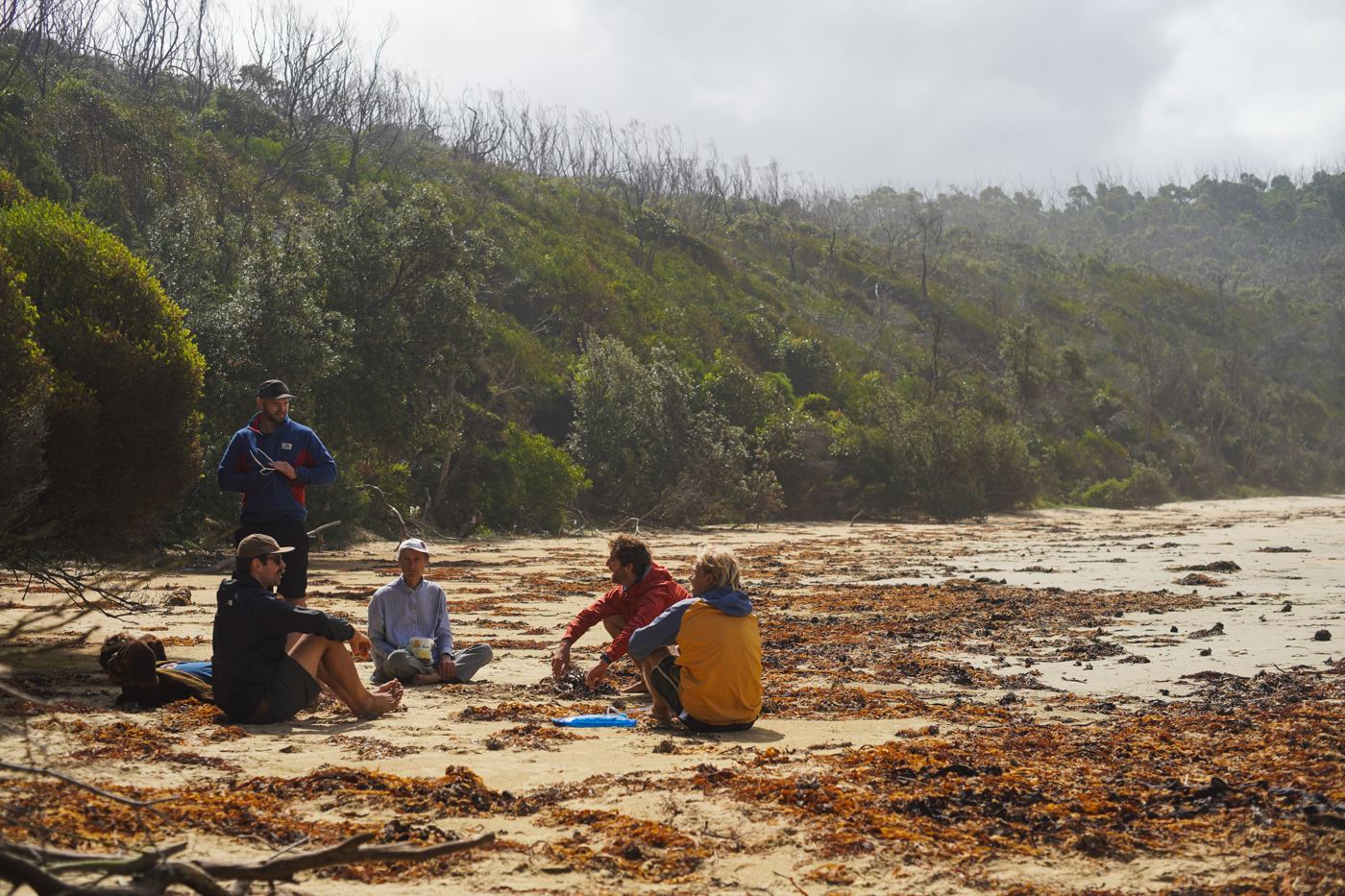 Men sitting in a loose circle on a beach